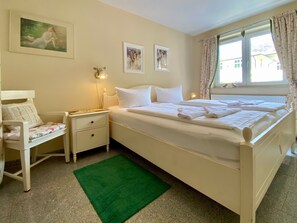 Une chambre à coucher avec un grand lit, une table de chevet, une chaise et un tapis vert.