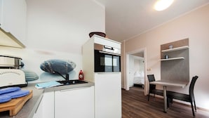 A compact kitchen with a microwave, oven, and sink. There is a dining area with a table and chairs. - Holiday home Lauterbach - Haus Grahl GM 69912 (Graal-Müritz)