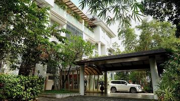 Un edificio moderno con entrada cubierta y un coche blanco estacionado en el interior.