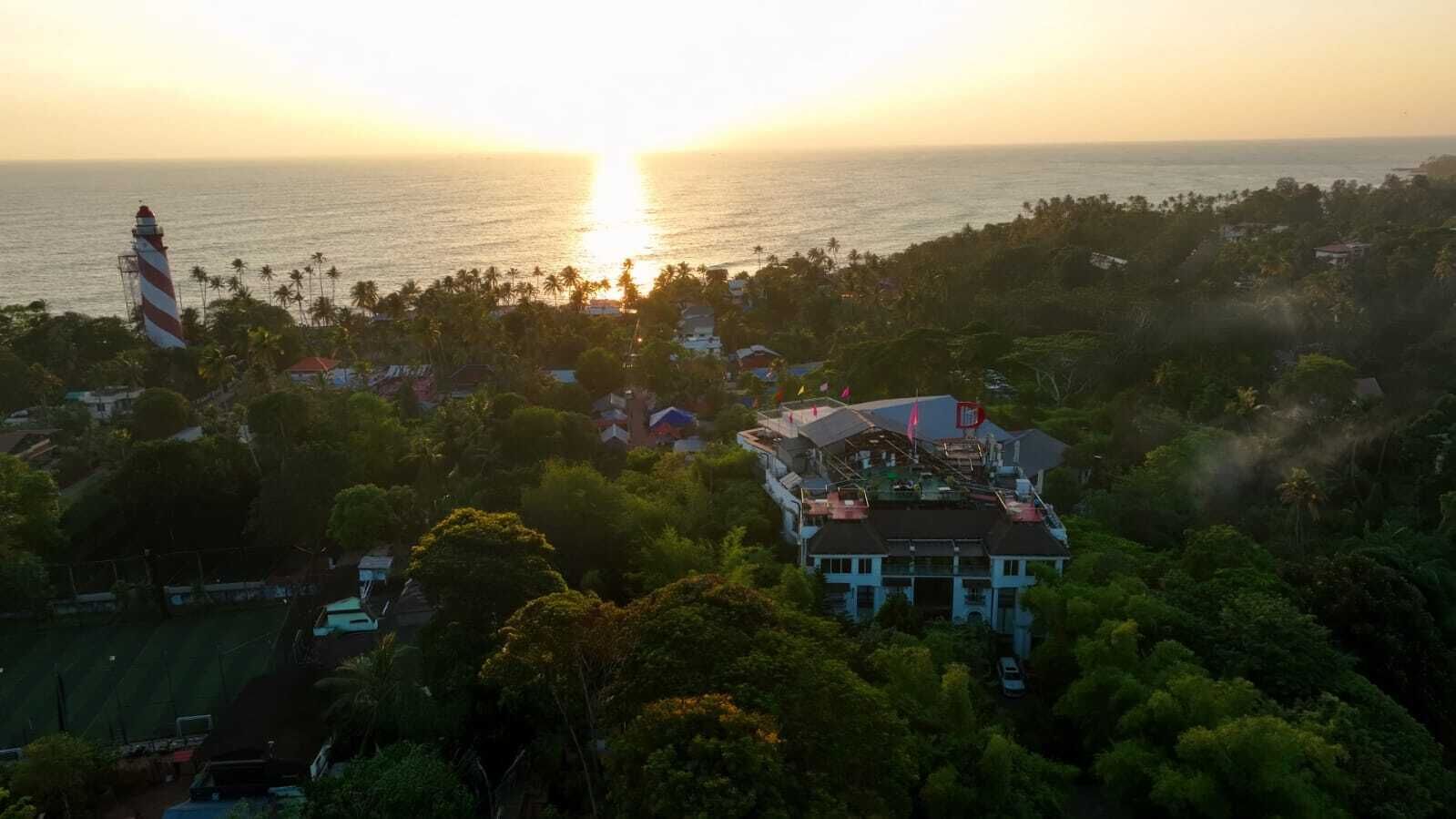 A coastal property with a large house, a lighthouse, and dense tropical vegetation.