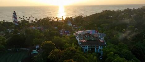 A coastal property with a large house, a lighthouse, and dense tropical vegetation.