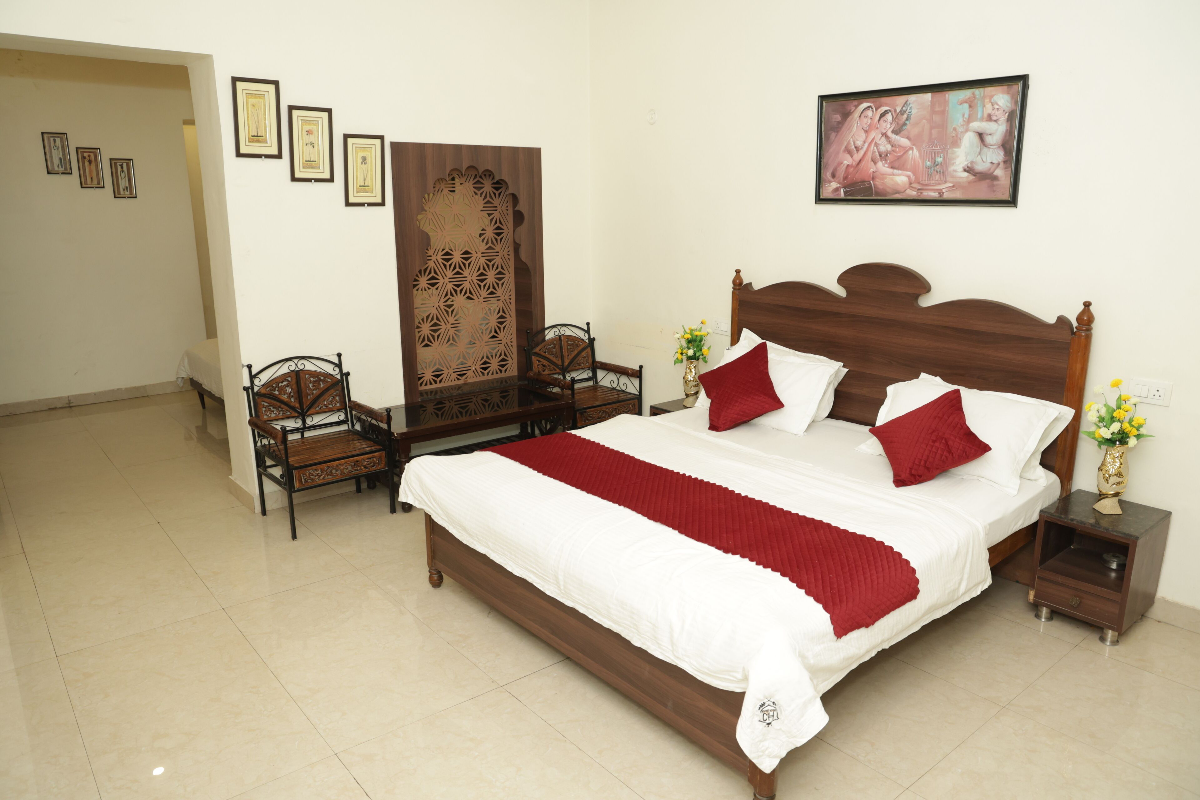 A neatly arranged bedroom with a large bed, two bedside tables, a chair, and a decorative screen.