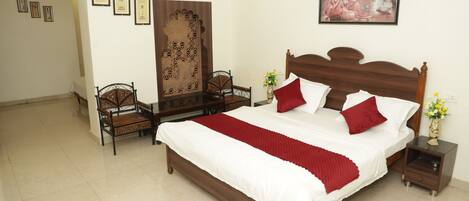 A neatly arranged bedroom with a large bed, two bedside tables, a chair, and a decorative screen.