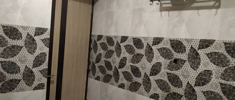 A bathroom with a wooden door, a towel rack with a white towel, and patterned tiles.