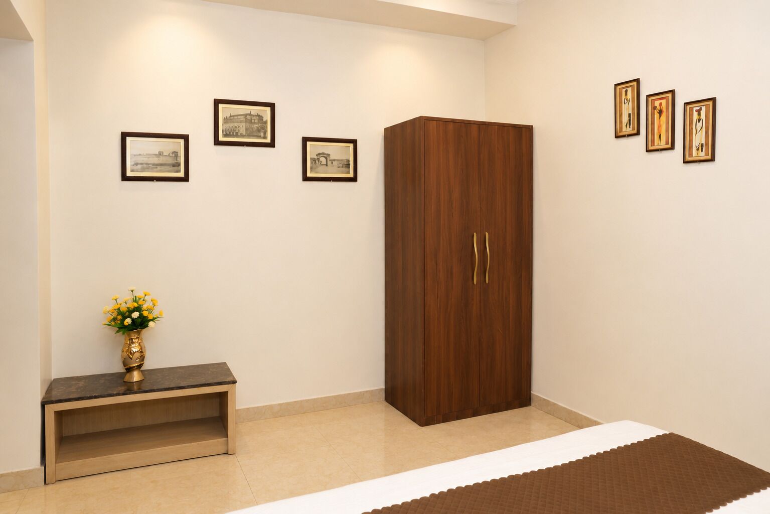 Una habitación con un armario, una consola con un florero, y tres cuadros en la pared.