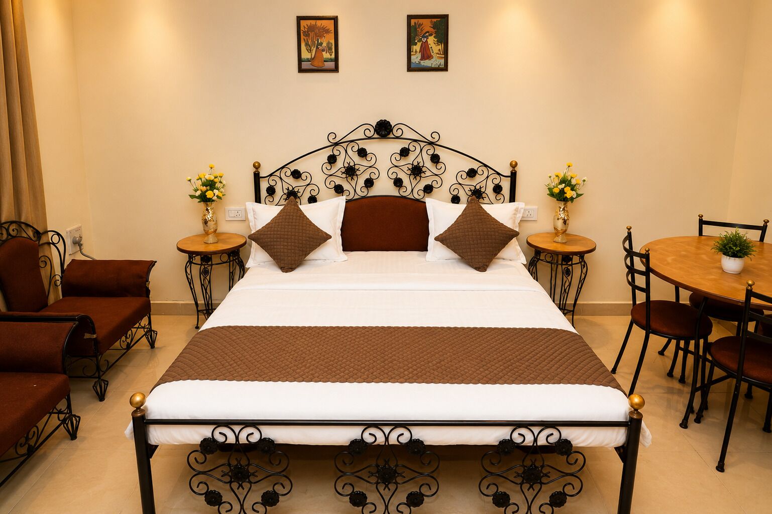 A neatly arranged hotel room with a bed, two side tables, a round dining table, and two armchairs.