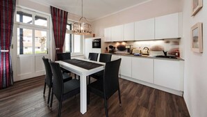 A modern kitchen with white cabinets, a dining table with black chairs, and a chandelier.