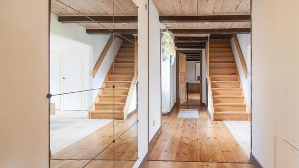 Ein Korridor mit Holzböden und einer Treppe, die zu einer oberen Ebene führt.