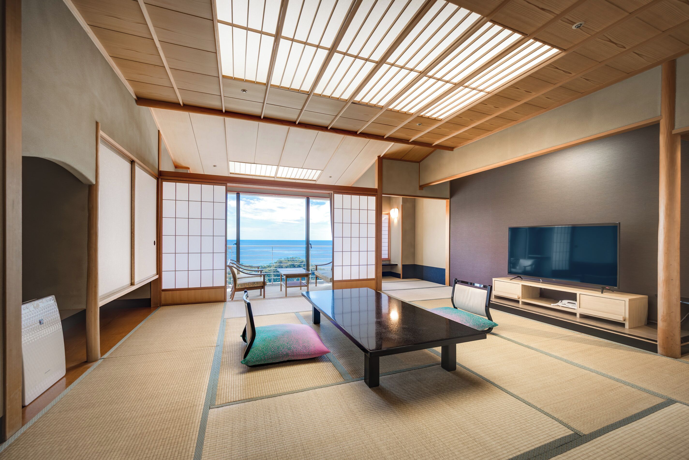Una habitación tradicional japonesa con suelo de tatami, una mesa baja y un televisor.
