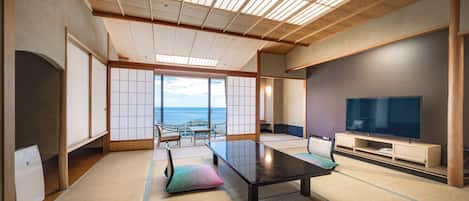 Una habitación tradicional japonesa con suelo de tatami, una mesa baja y un televisor.