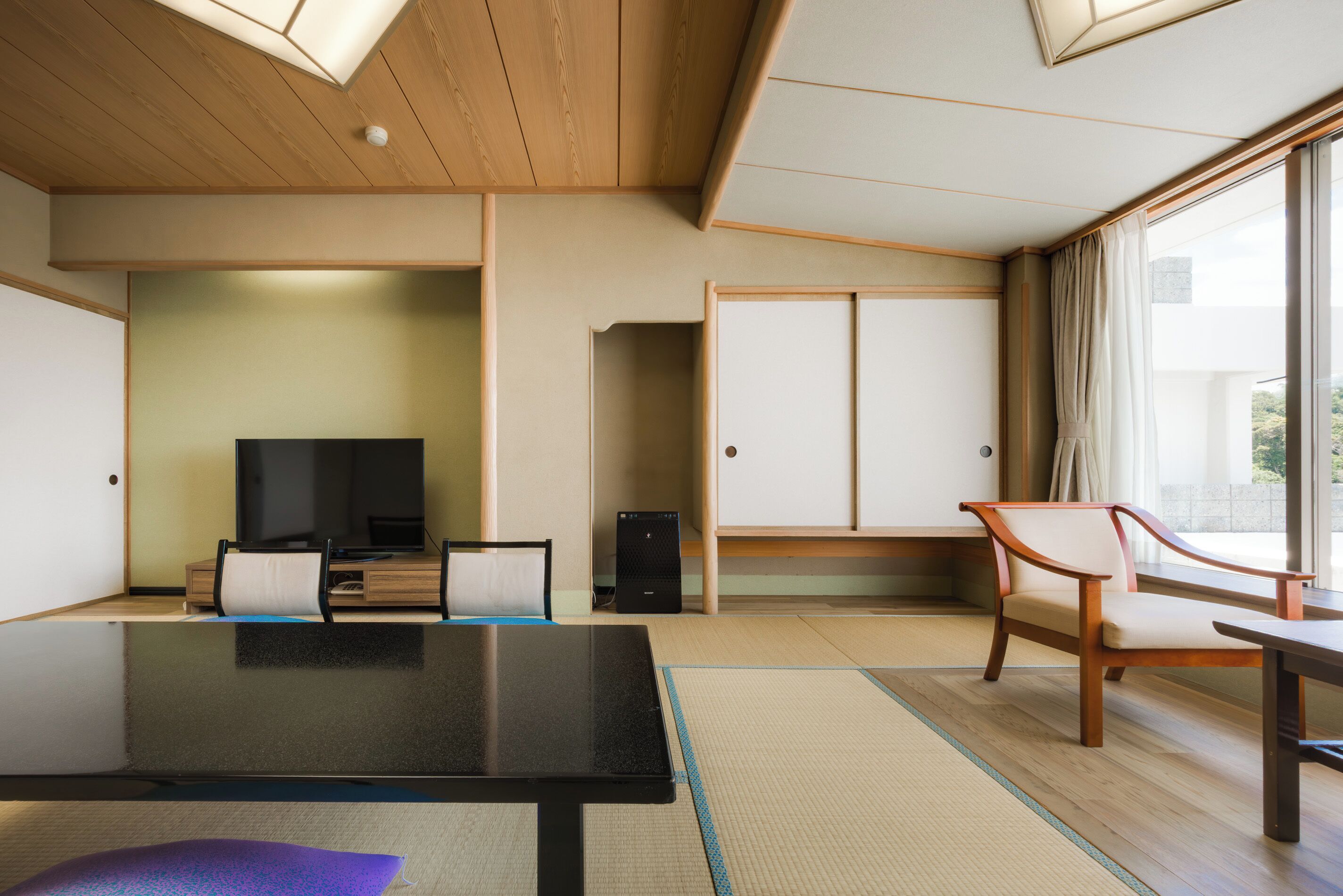A modern hotel room with a large bed, a TV, a desk, and a chair.