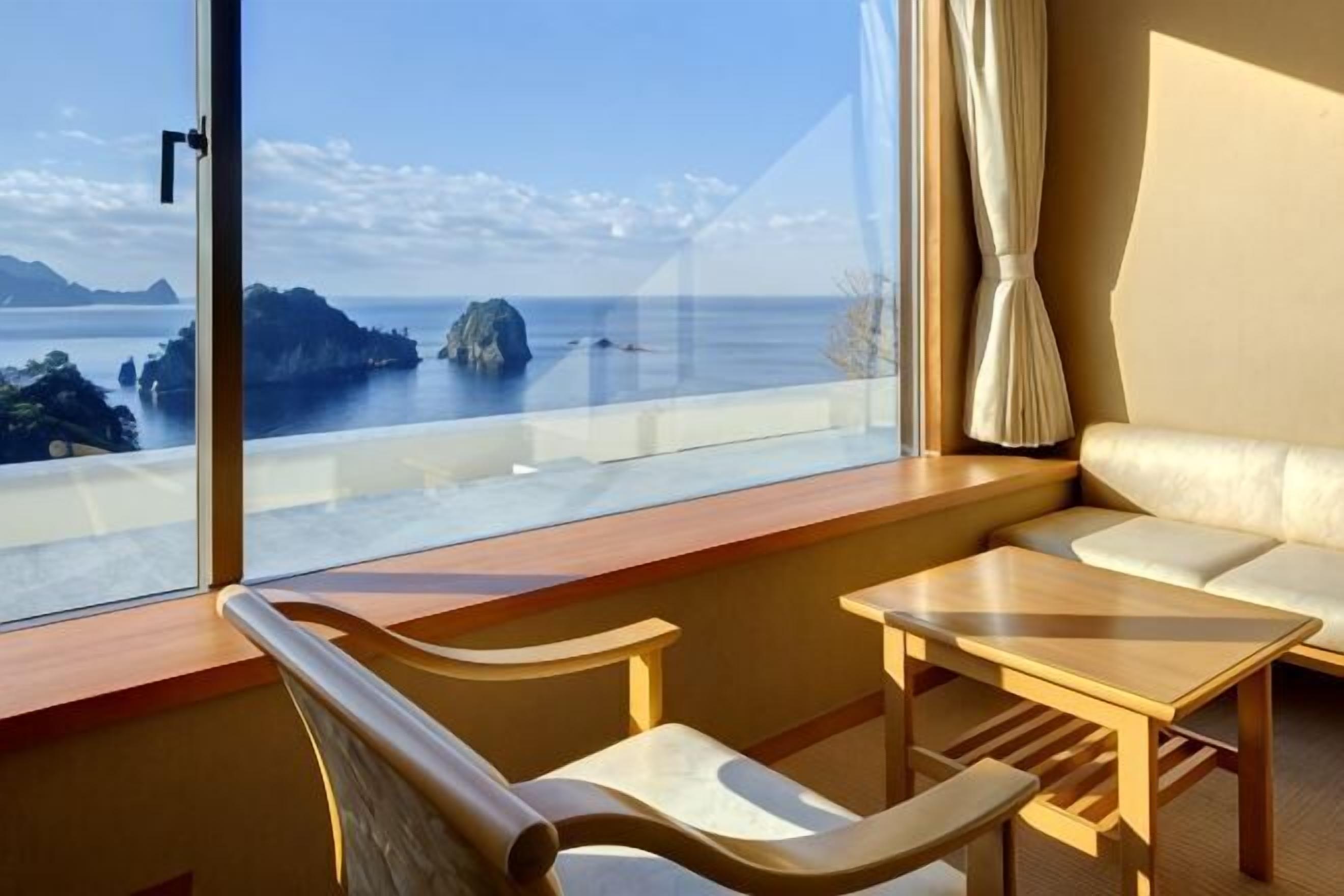 Quarto com vista para o mar, um sofá e uma mesa de madeira.