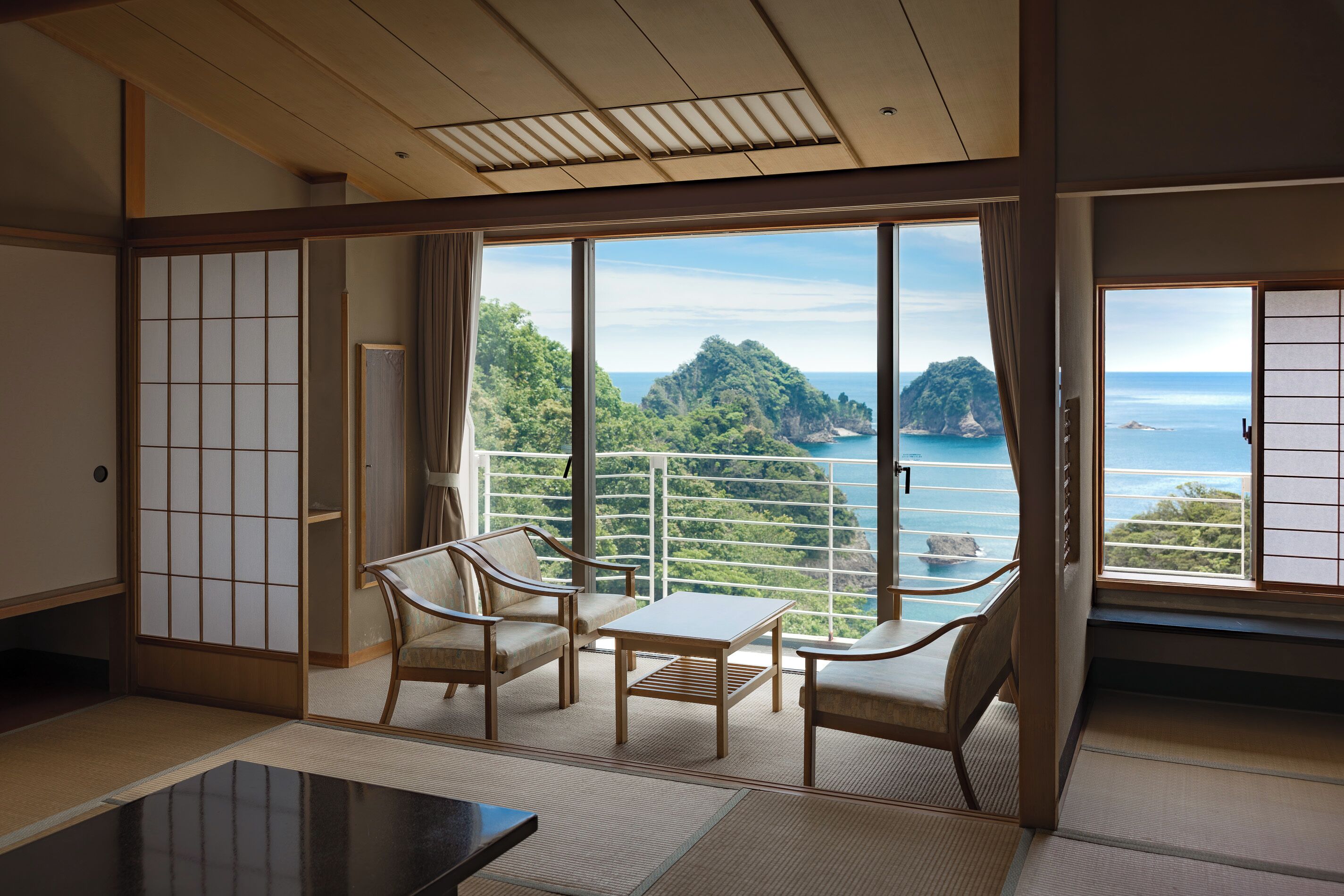 Een traditionele Japanse kamer met tatami vloeren, een lage tafel, twee stoelen en een verschuifbare shoji-scherm.