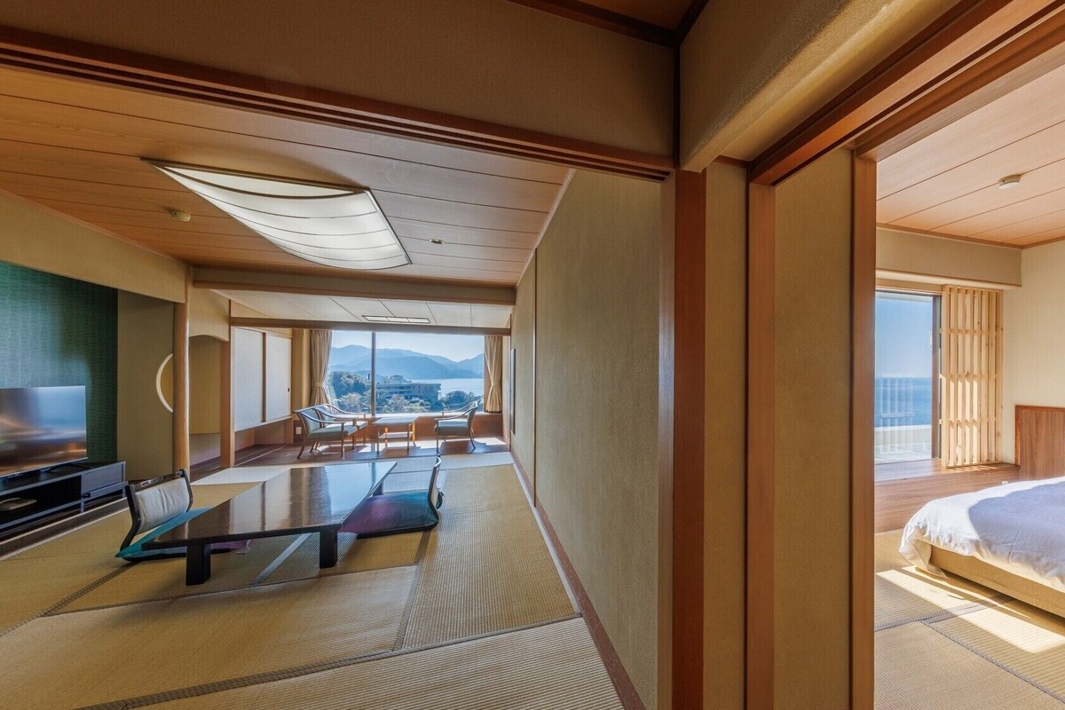 Ein Hotelzimmer mit einem Bett, einem Fernseher, einer Sitzecke mit Blick und einem großen Fenster.