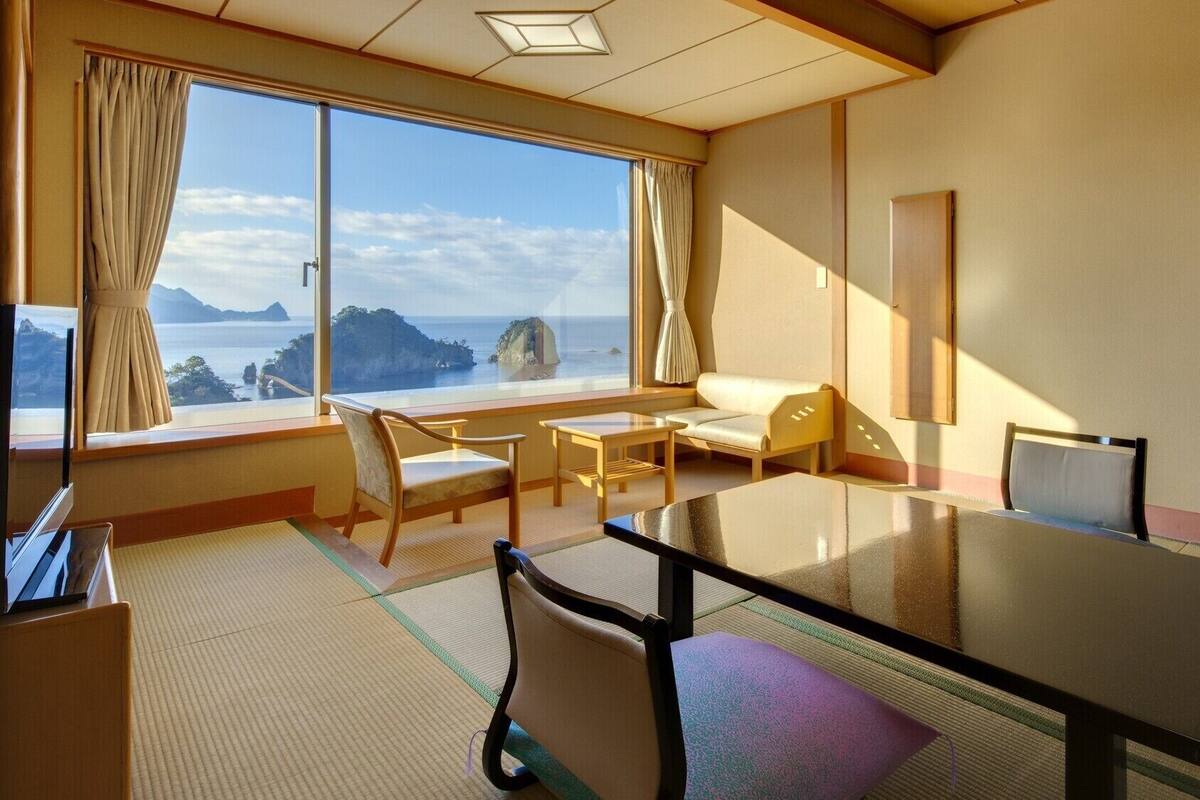Une chambre d’hôtel avec une grande fenêtre, un canapé, une table et un téléviseur.
