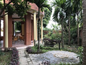 A covered outdoor seating area with brick pillars and wicker furniture.