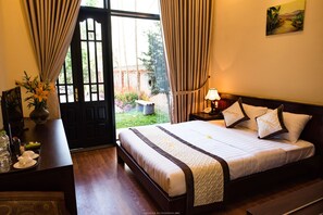 A hotel room with a bed, bedside tables, a desk, and a view of the outdoors.