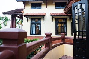 A building with a balcony, a black door, and windows with shutters.