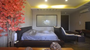A modern bedroom with a bed, a chair, a desk, and a large window.