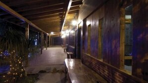 A covered outdoor area with benches and a pathway leading to a building with windows.