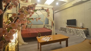 A bedroom with a canopy bed, a television, and a dining table.