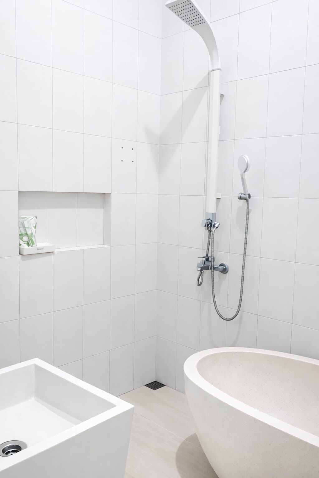 Ein modernes Badezimmer mit einer freistehenden Badewanne, einer Dusche inklusive Handbrause und einer kleinen Ablage für Pflegeprodukte.
