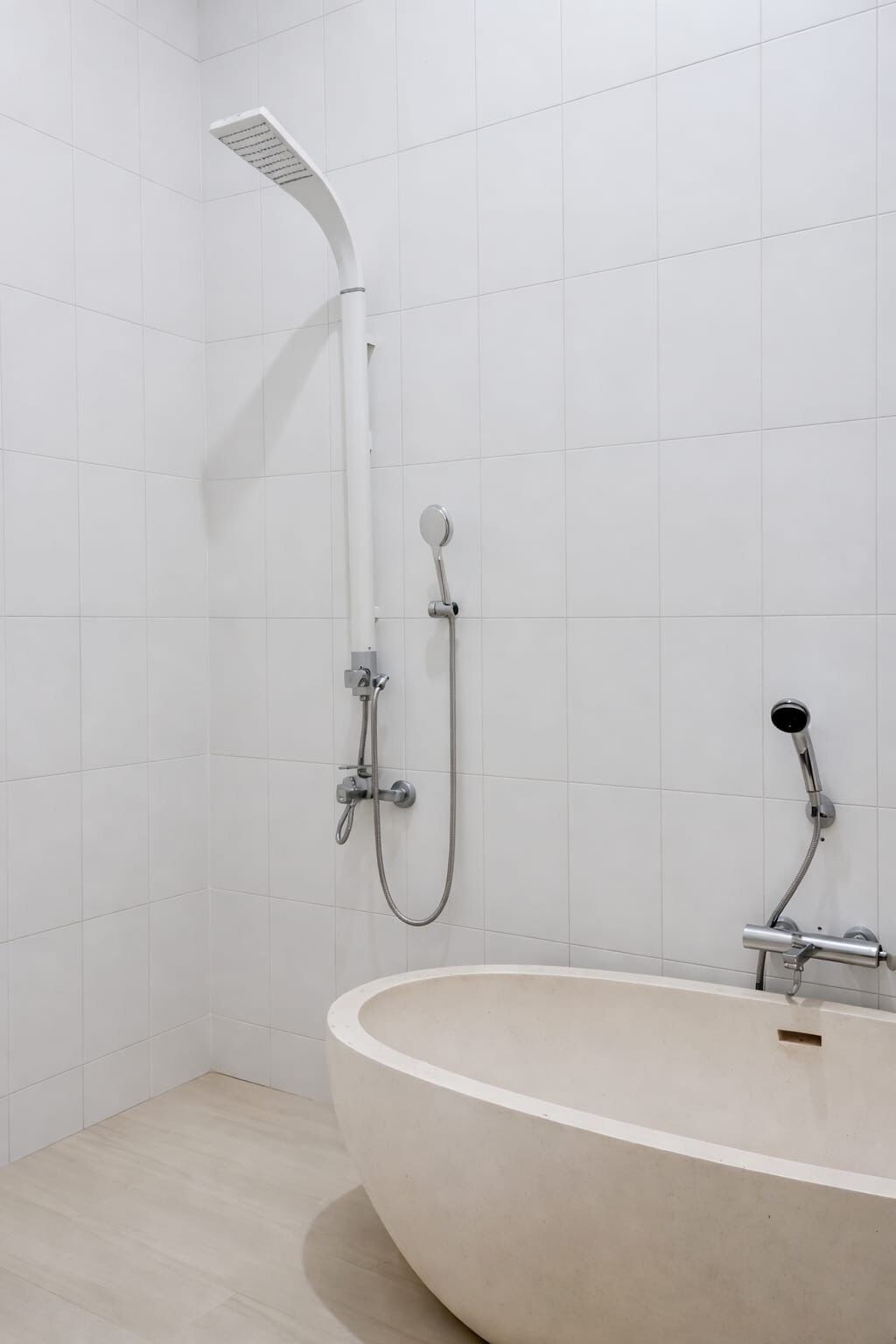 A bathroom with a freestanding bathtub, a handheld showerhead, and a wall-mounted showerhead.