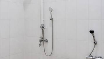 A bathroom with a freestanding bathtub, a handheld showerhead, and a wall-mounted showerhead.
