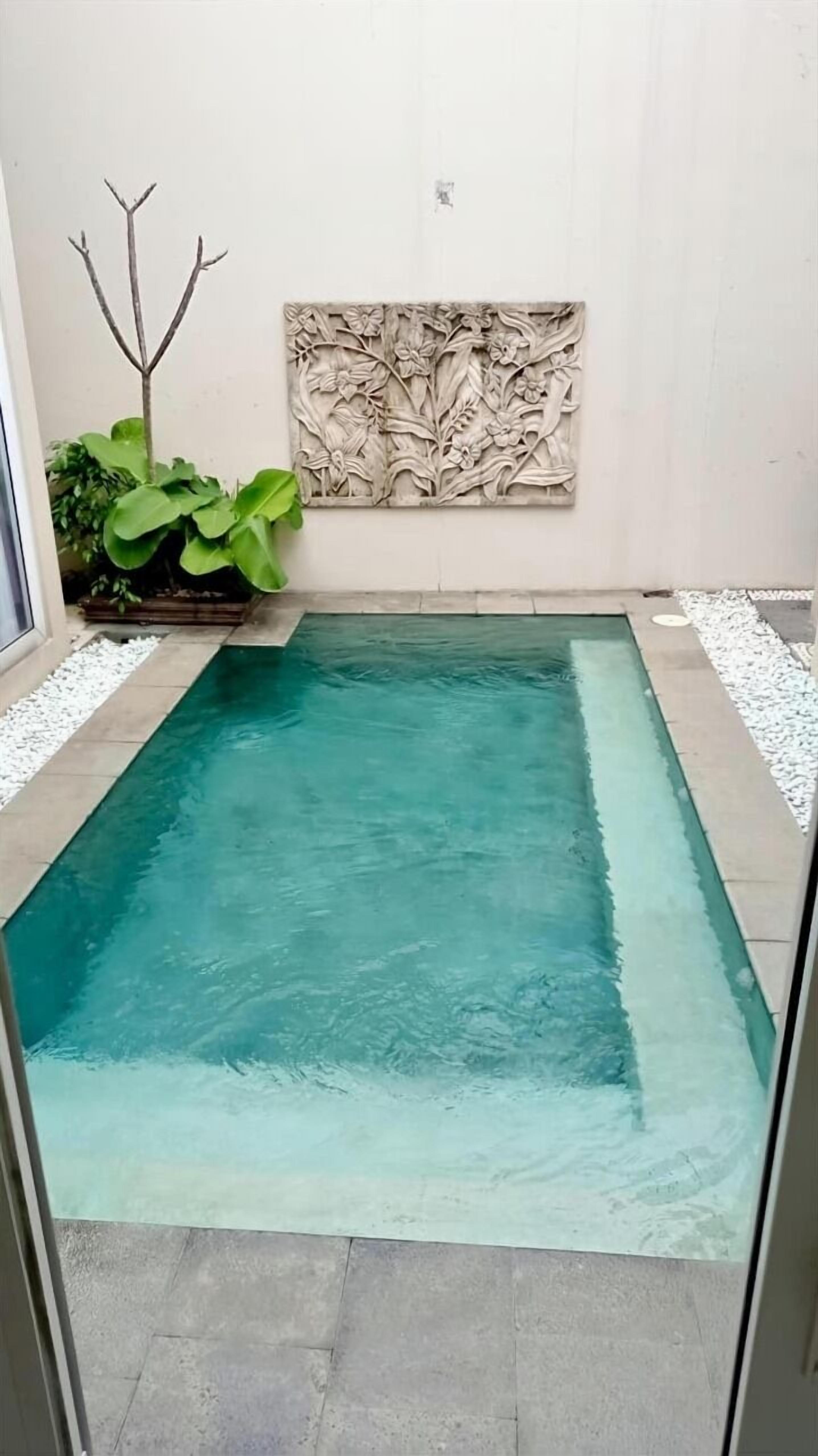 A rectangular pool with clear water, surrounded by a tiled deck and white pebbles.