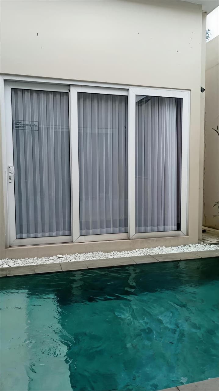 A swimming pool with a clear blue water surface, surrounded by a light-colored deck.