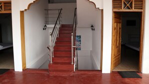 A staircase with a wooden handrail and a red carpet leading to a room with a wooden door and a window. - Nilaveli Star View Hotel (Nilaveli)