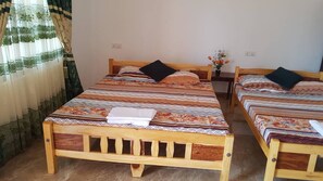 A room with two wooden beds, each with patterned bedding and pillows.