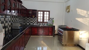 A kitchen with a checkered backsplash, a window, a stove, and a microwave. - Nilaveli Star View Hotel (Nilaveli)