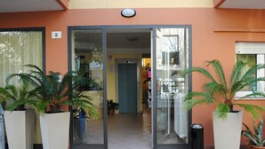 A building entrance with a glass door, number 8, and potted plants on either side. - Hotel Frida (Rimini)