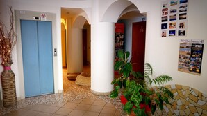 A hotel lobby with a blue door, a tiled floor, and a poster on the wall. - Hotel Frida (Rimini)