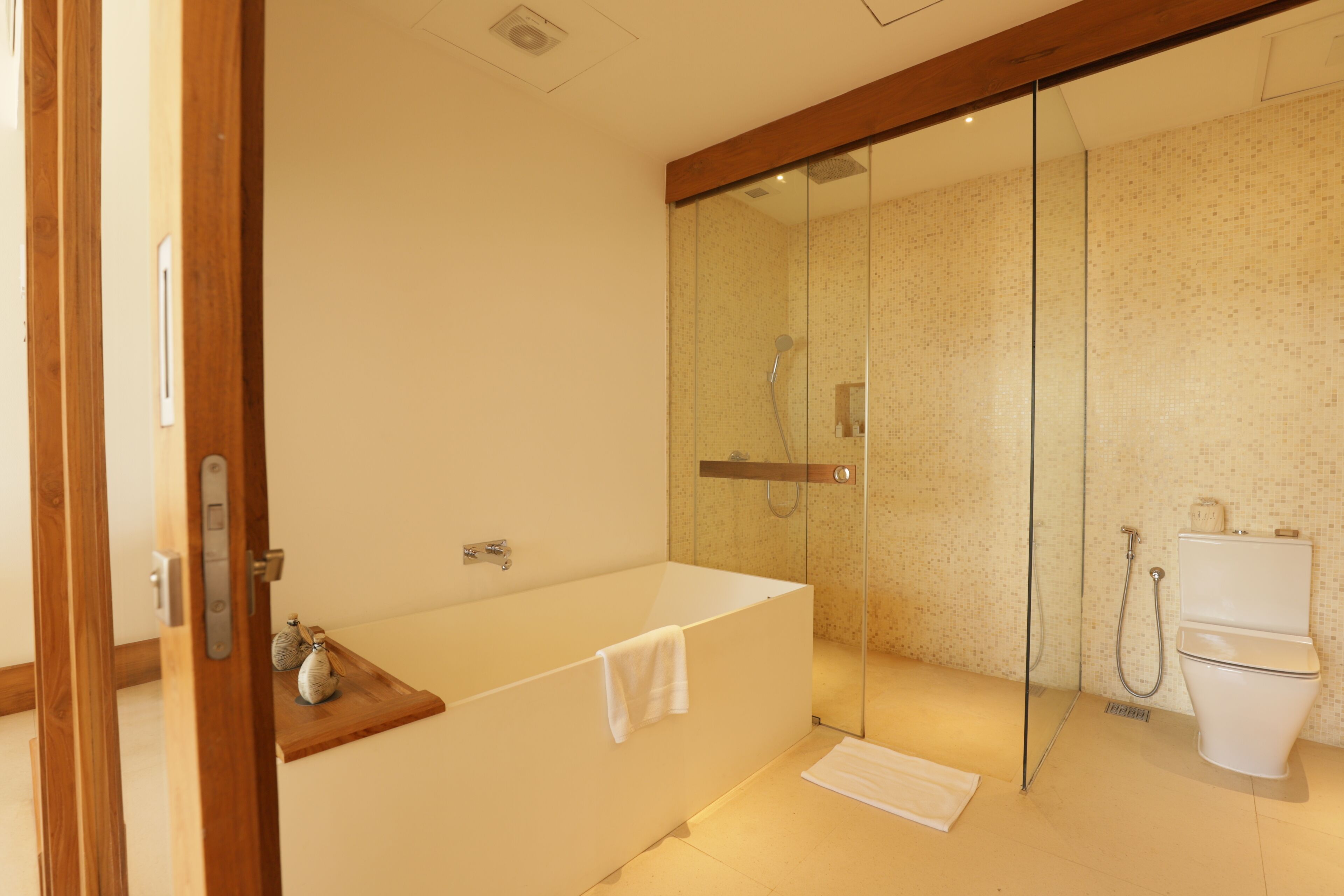 Un baño moderno con ducha de vidrio, una bañera con una toalla y un inodoro.
