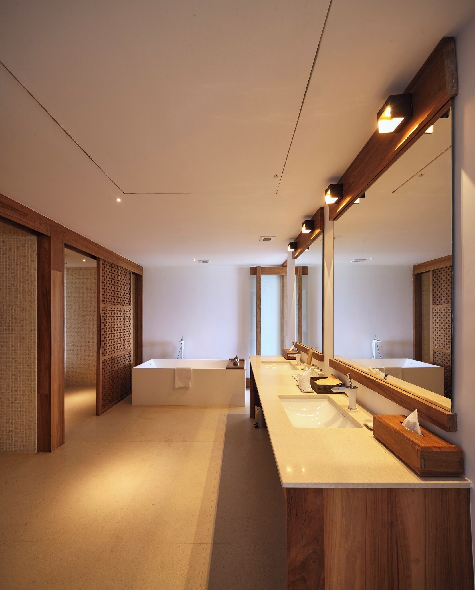 A modern bathroom with a long vanity, a large mirror, and a bathtub.