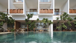 A multi-story hotel with a central swimming pool, outdoor seating, and wooden balconies.