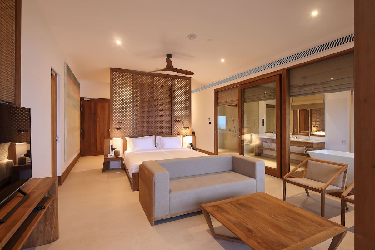 Quarto moderno com cama, sofá e mesa de centro de madeira.