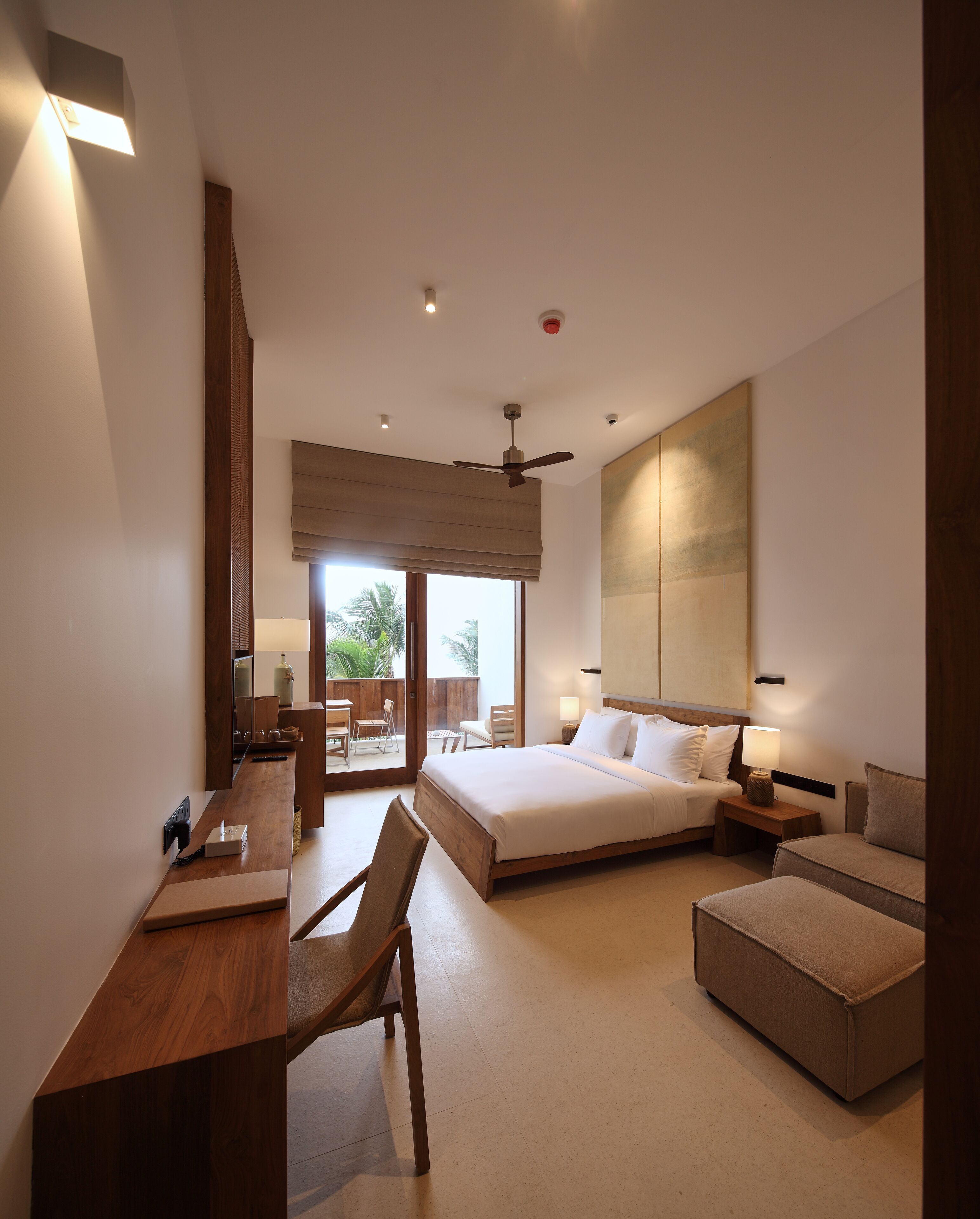 A modern hotel room with a large bed, a desk, and a seating area.