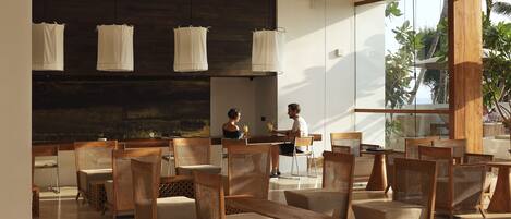 Un espacio interior amplio con muebles de madera, ventanas grandes y vistas al exterior.