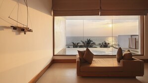 A modern room with a large window overlooking the sea, a sofa with cushions, and a minimalist art piece on the wall. - Riff Hikkaduwa (Hikkaduwa)