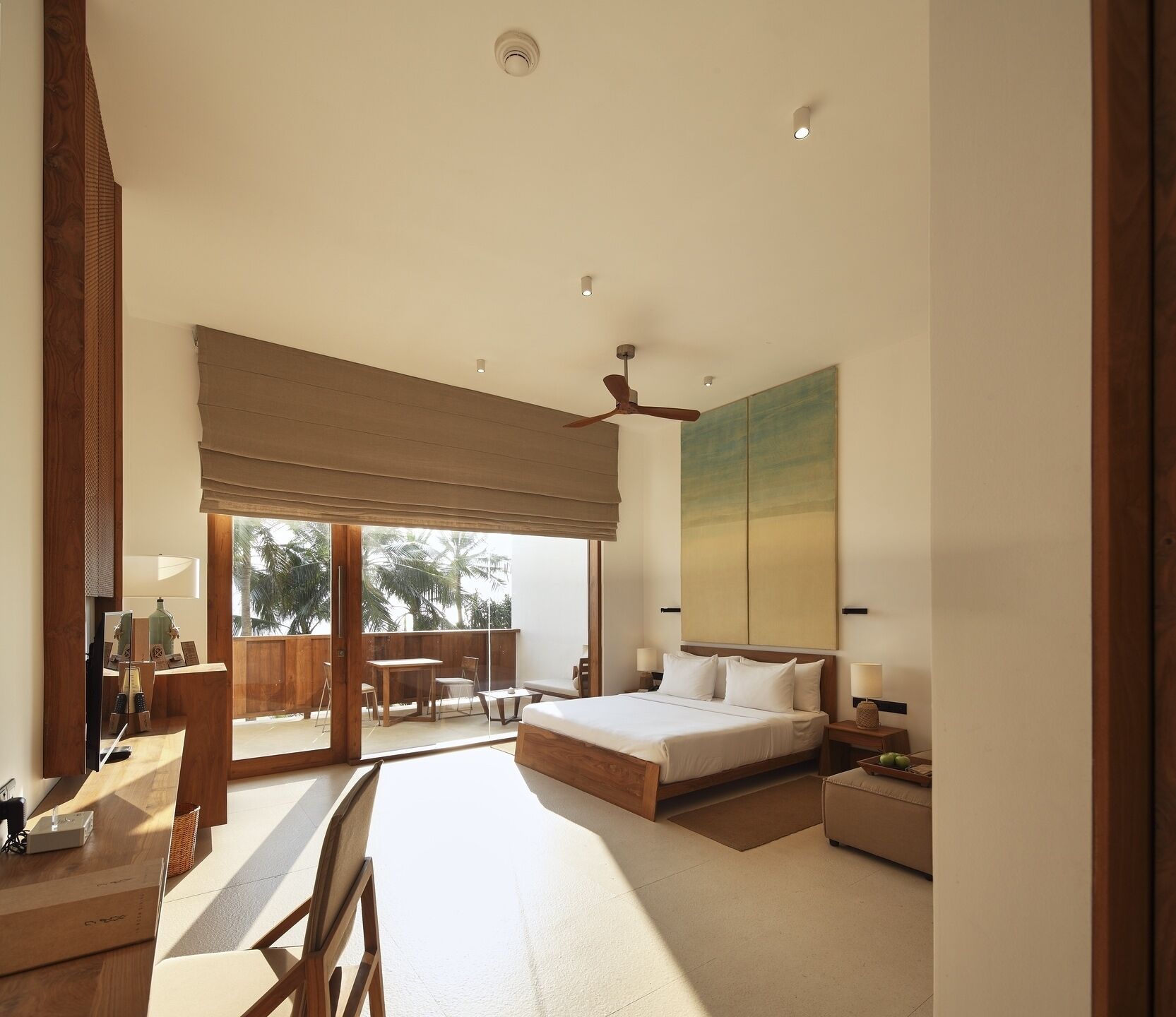 A modern bedroom with a large bed, a ceiling fan, and a view of the outdoors.