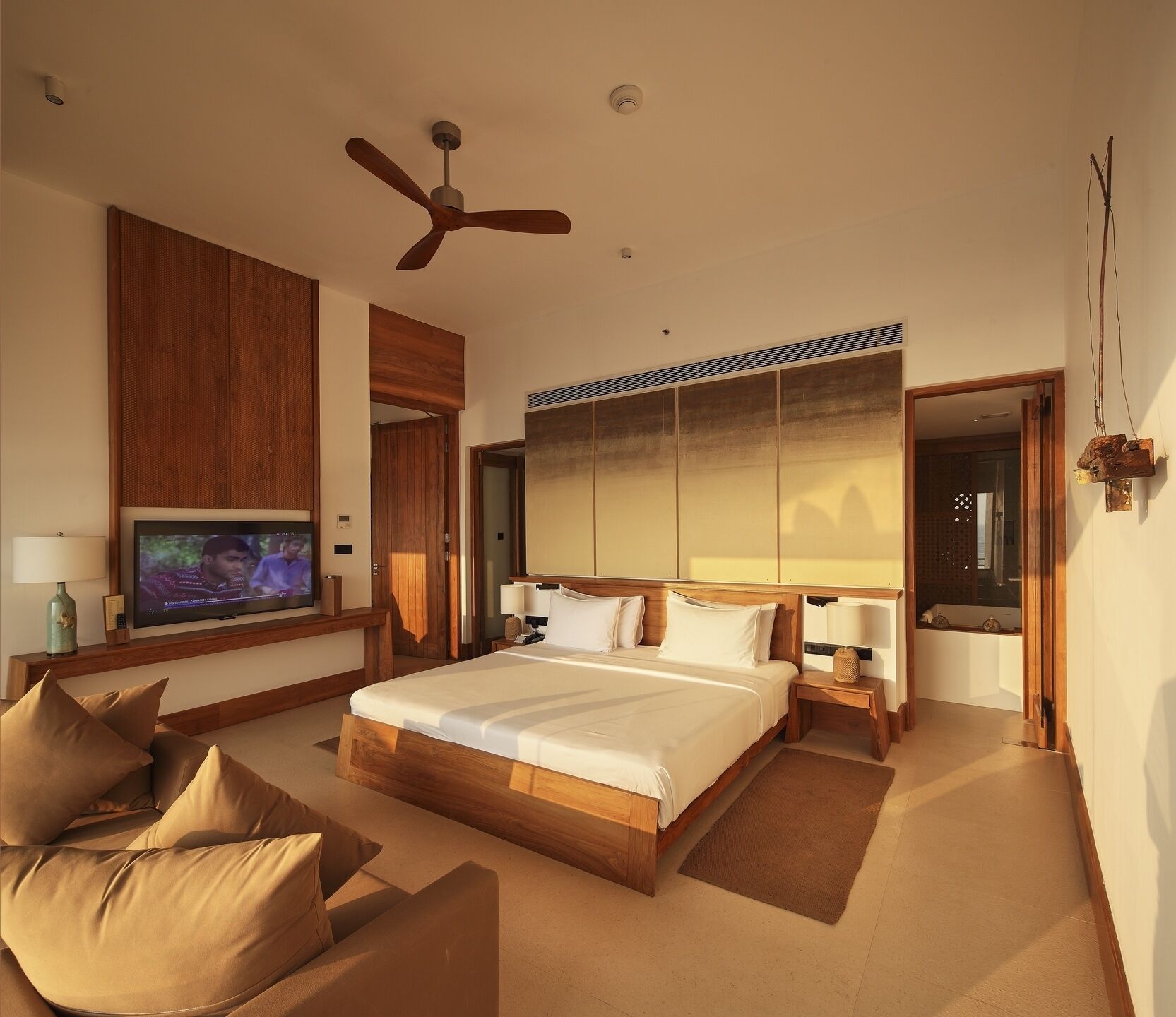 Un dormitorio amplio con una cama grande, ventilador de techo, televisor y cabecero de madera.