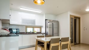 Une cuisine moderne avec des meubles blancs, un réfrigérateur en acier inoxydable et une table à manger avec des chaises.