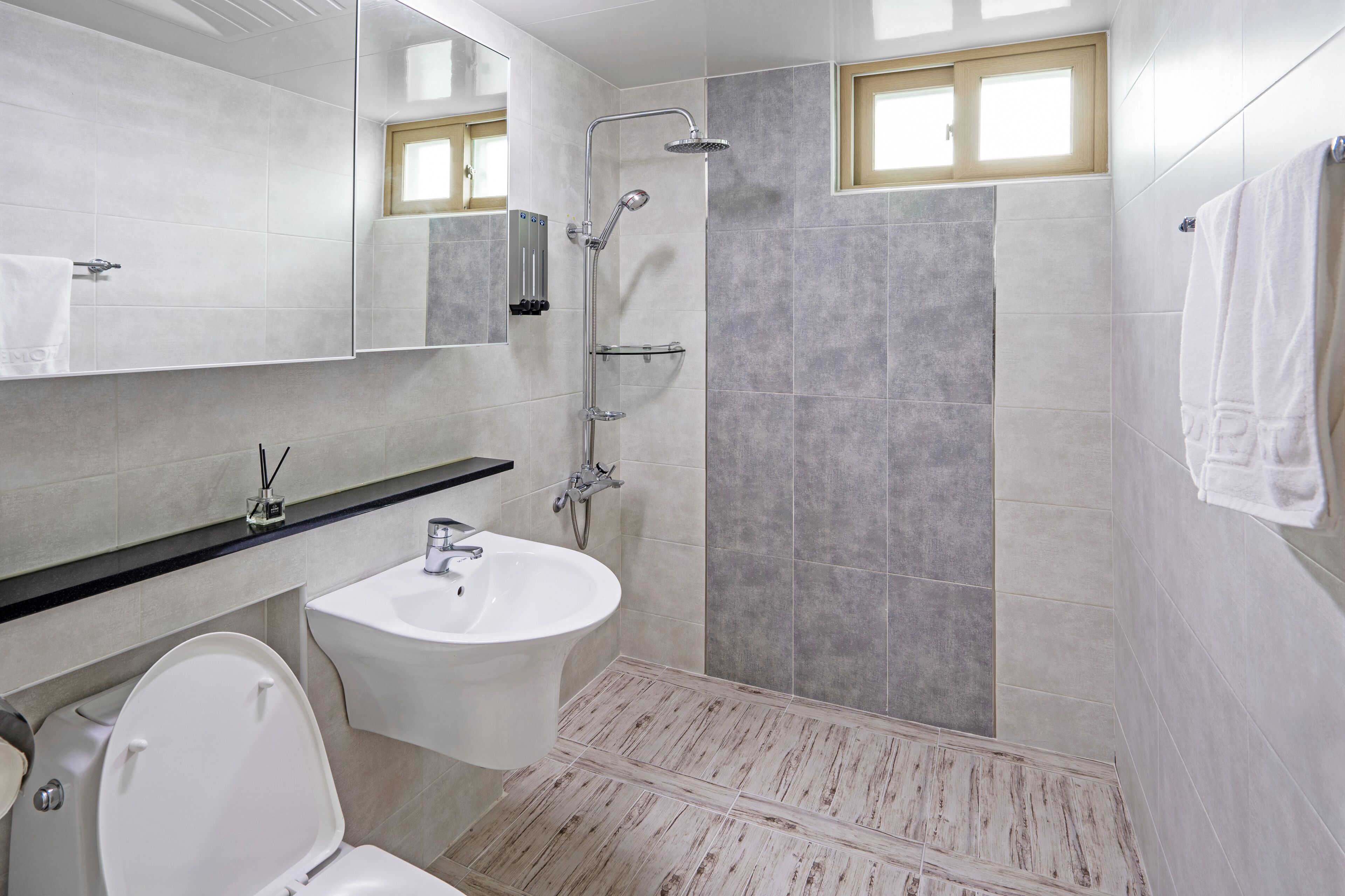 A modern bathroom with a shower, sink, and toilet.