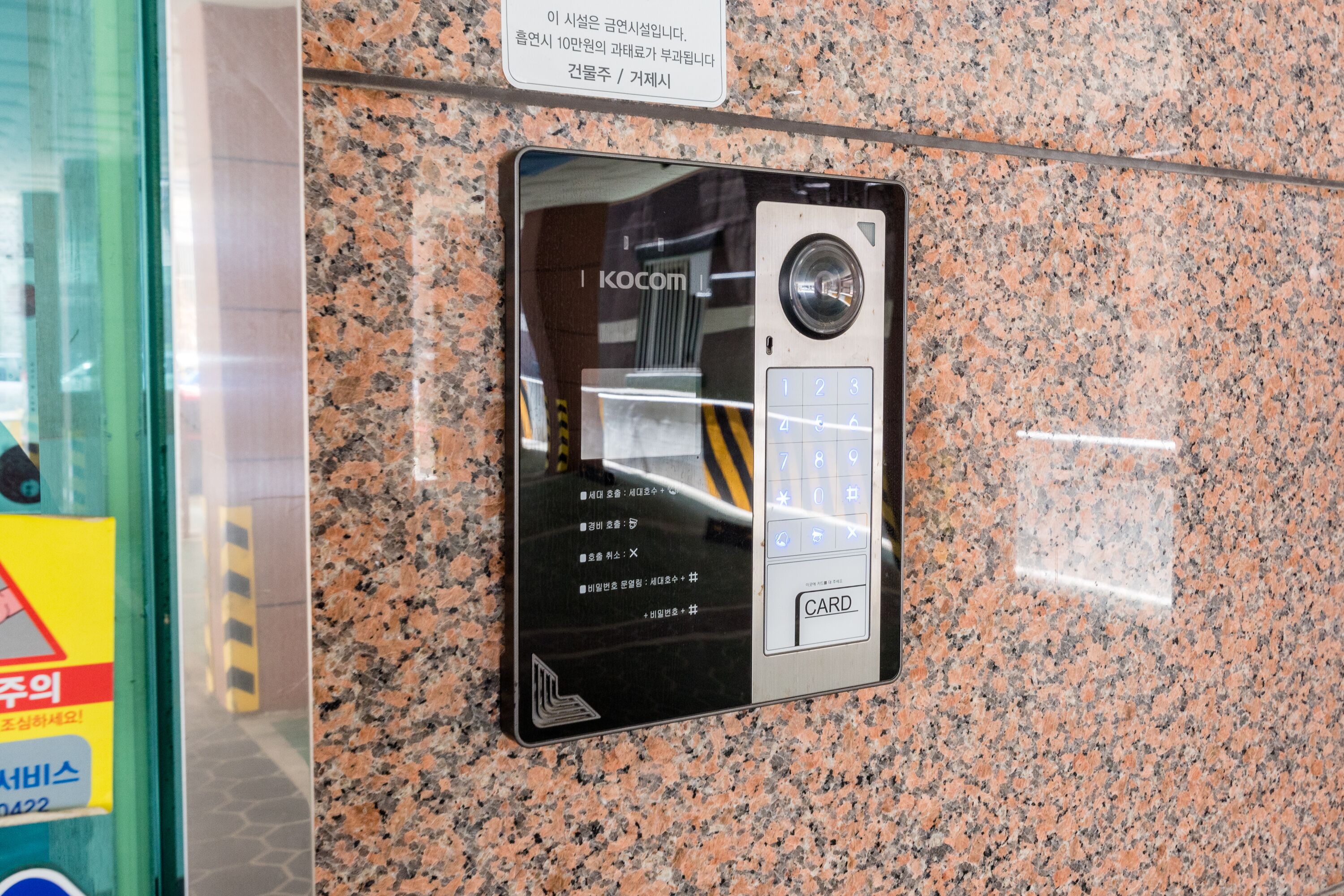 Una postazione di sicurezza con lettore di carte e tastierino, fissata a un muro in granito.