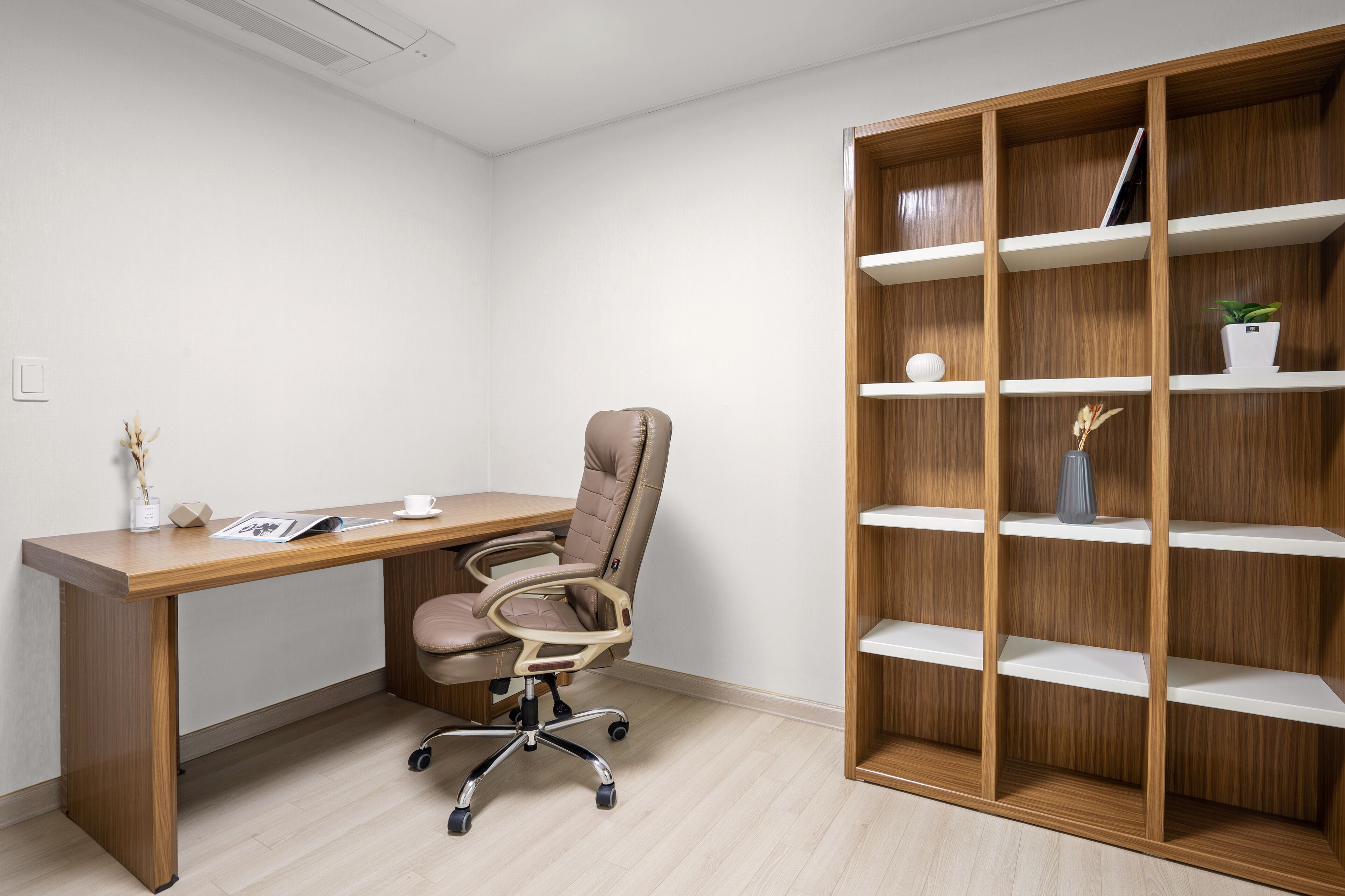 Un bureau moderne avec un bureau en bois, une chaise de bureau et une bibliothèque intégrée.