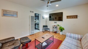 Una sala de estar con ventilador de techo, televisor de pantalla plana, sofá, mesa de centro y comedor.