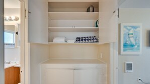 Un armario blanco con un mueble inferior, una toalla y un bolso estampado.
